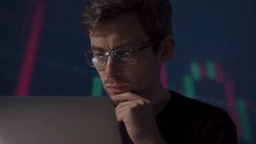 Young trader with glasses monitors the financial market on his computer, immersed in crypto charts, stock indexes, and economic graphs forecasting a possible global recession - Powered by Shutterstock - Get 15% off with code: PIKWIZARD15