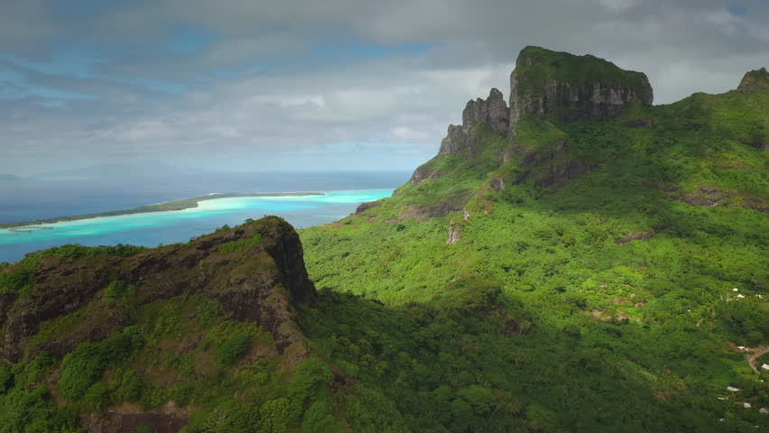 Stunning landscape highlighting vibrant green mountain terrain overlooking a striking blue lagoon under partly cloudy skies, capturing nature