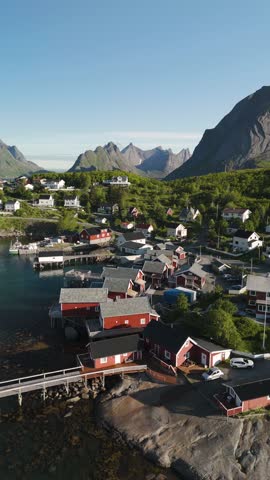 Discover a picturesque coastal village in Lofoten Reine Norway with vibrant red houses, nestled between towering mountains.