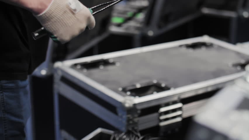 Worker coiling cables above transport case