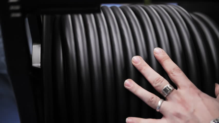 Hand touching coiled stage cable on reel