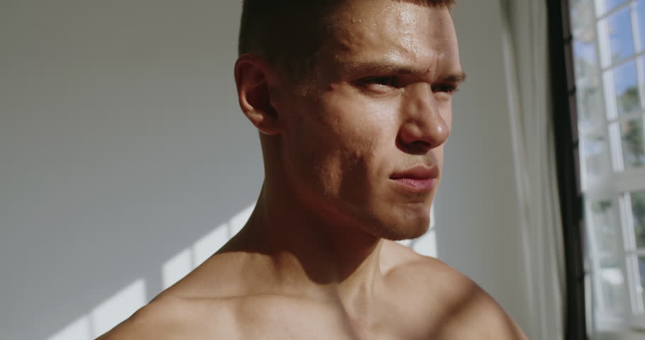 A focused young man with an athletic build trains intensely in a studio setting, showcasing strength and determination. Athletic Man Engaged in Studio Physical Training