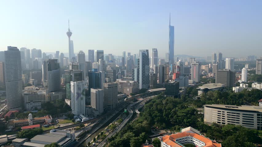 Aerial view of downtown Kuala Lumpur with modern skyscrapers, highways, and urban skyline.