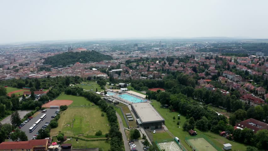 wide side drone shot of public outdoor swimming pool and castle in brno city