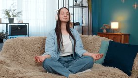 Young pretty woman at home calmly relaxing with closed eyes, quietly breathing listening meditation music in headphones. Caucasian girl peacefully meditating on sofa, feeling tranquility, mindfulness. - Powered by Shutterstock - Get 15% off with code: PIKWIZARD15
