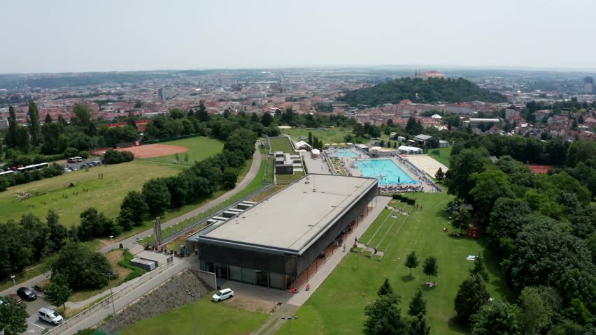 side drone shot of public outdoor swimming pool and castle in brno city