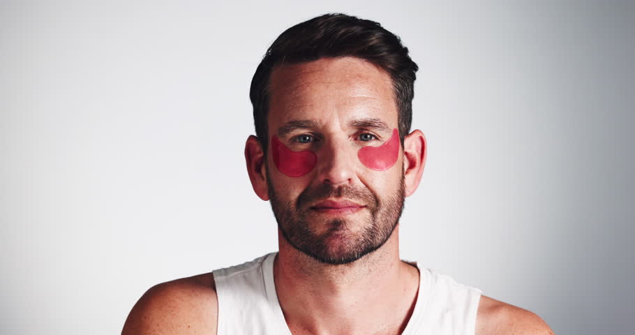 Eye mask, face and skincare with happy man in studio for antiaging, dermatology or moisturizing. Cosmetics, beauty and hydration with smile of person on gray background for aesthetic or wellness