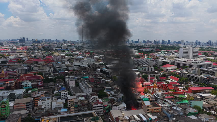 Alarming fire in a burning building in the middle of the dense cityscape of Bangkok Thailand