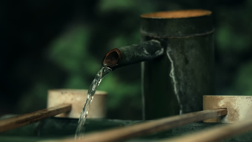 Bamboo Temizuya with Flowing Water and Wooden Ladles at a Temple in a Green Forest