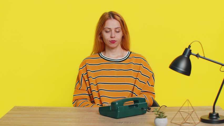 Call me. Woman looking at camera advertising phone call having conversation on wired old-fashioned retro telephone. Call center or support service operator helpline hotline. Girl on yellow background