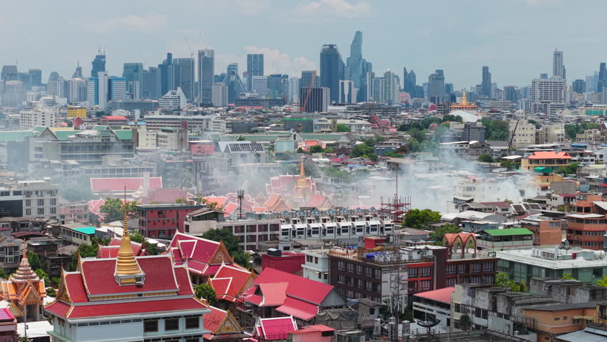 Smoke rises over Bangkok's cityscape and the rooftops of traditional temples on May 8 2025