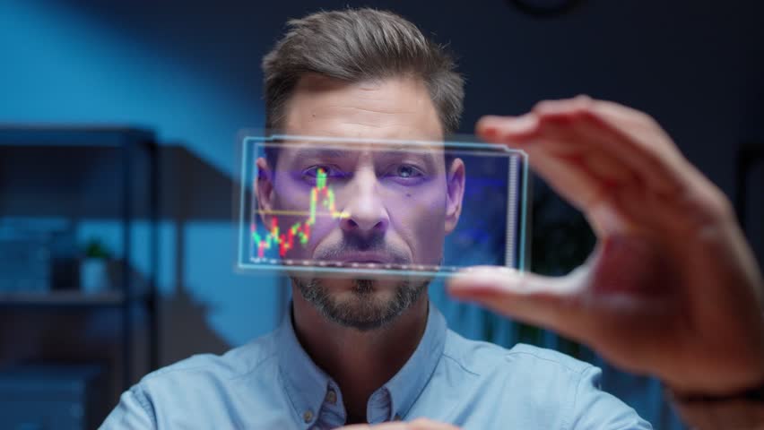 Focused bearded man holding transparent digital screen while analyzing financial chart. Active live stock market data reflecting on futuristic interface. Advanced technology device. - Powered by Shutterstock - Get 15% off with code: PIKWIZARD15