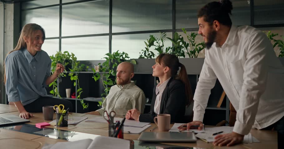 Office worker shares ideas and discusses projects with colleagues at the table engaging in casual conversation during a break from work