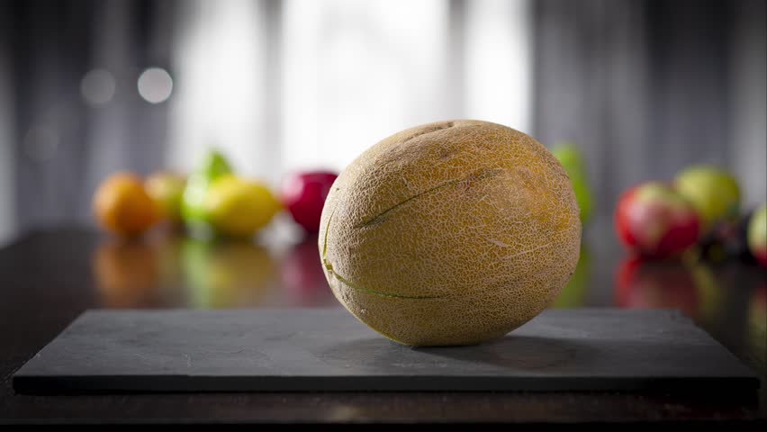 Creative food animation of sliced cantaloupe melon pieces moving across a dark stone surface and rising into a transparent glass bowl. Fresh, juicy, and minimalistic fruit presentation, ideal for heal