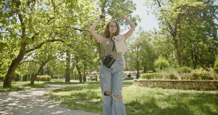 Young woman enjoys a beautiful day in the park, expressing carefree happiness and enjoying the fresh air and sunshine.