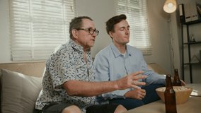 Father and son cheer enthusiastically while watching a sports game on TV, holding beer bottles and popcorn bowl. - Powered by Shutterstock - Get 15% off with code: PIKWIZARD15
