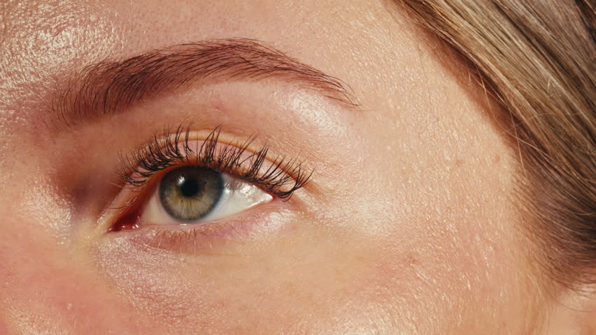 Close-up womans blinking eye with long eyelash and contact lens. Beauty make up of green eye with neon light.