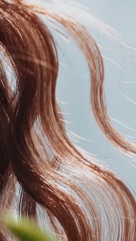 Woman with curly red hair locks waved by light wind at bright sunlight closeup slow motion. Pretty lady with elegant hairstyle. Beauty and fashion