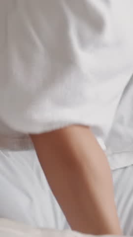 Joyful young couple in bathrobes jumps on large bed in hotel room closeup slow motion. Spending honeymoon at resort. Family romantic journey