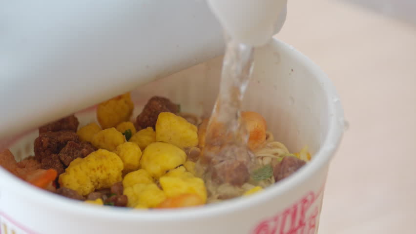 Pour boiling water into instant ramen in a disposable cup. Busy modern lifestyle. Easy and quick cooking. Japanese food culture