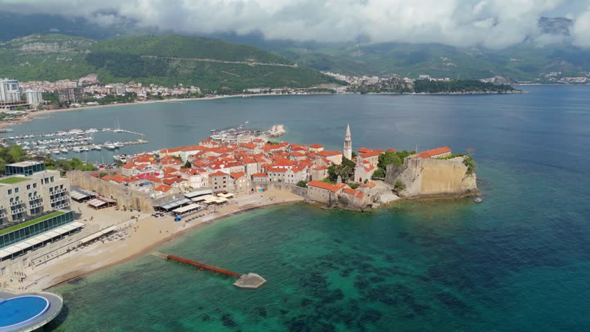 Aerial view of the walled old town of Budva. Pier with yachts and moored boats. Adriatic Sea, Montenegro