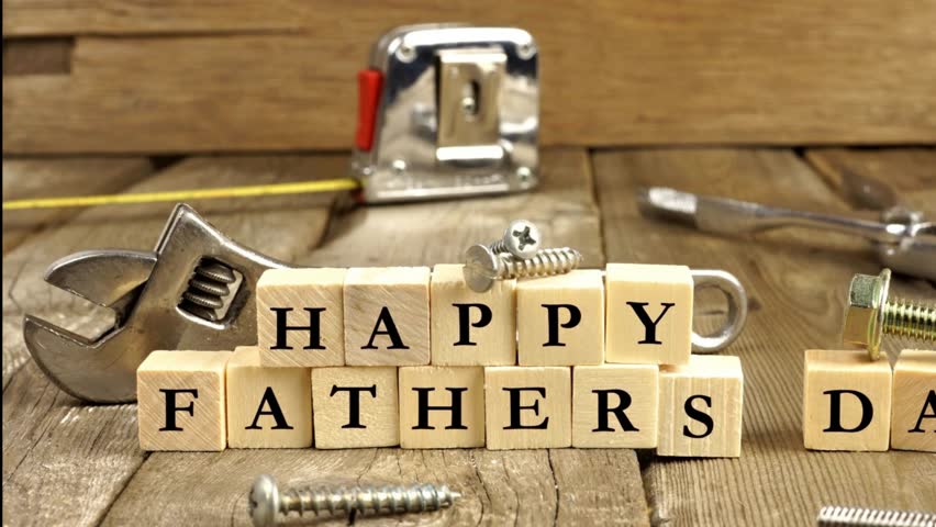 Happy Fathers Day greeting on wooden blocks with tools. Slow panning motion video.