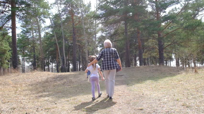 Sunny autumn day. Grandmother walking with grandchild in the forest, bird watching. Family vacations. Recreation pursuit. Healthy activity lifestyle.