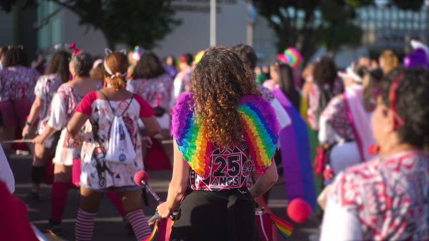 Gay woman wear rainbow fallen angel wings. Happy orchestra party. Carnival outfit. Bi girl walk lgbt pride fest. Lgbtq musical show. Colorful feathers Joy parade march play drums festival performance