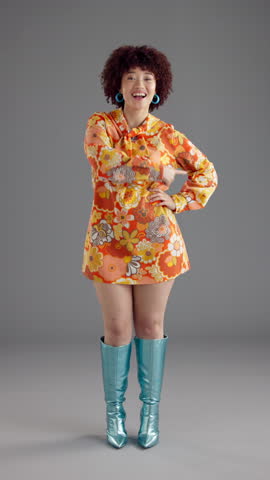 Face, dancing and woman with fashion, retro clothes and energy on gray background. Happy person, model and vintage outfit with movement, stylish wardrobe and dress with smile, trendy and colourful