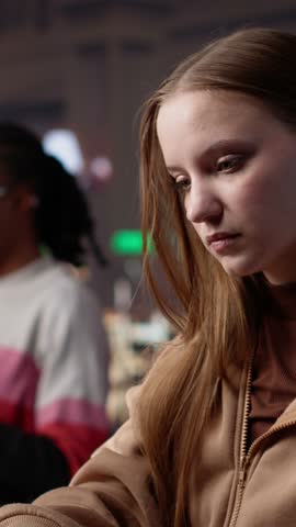 Vertical Video Student struggling to stay focused and awake while she does her research, writing on bachelor paper in the library to obtain college diploma. Girl working hard for a certificate. Camera