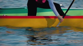 A brightly colored canoe sweeps across the clear waters. Close-up of a girl paddling a canoe. Colorful hull reflects shimmering waves. Slow motion - Powered by Shutterstock - Get 15% off with code: PIKWIZARD15