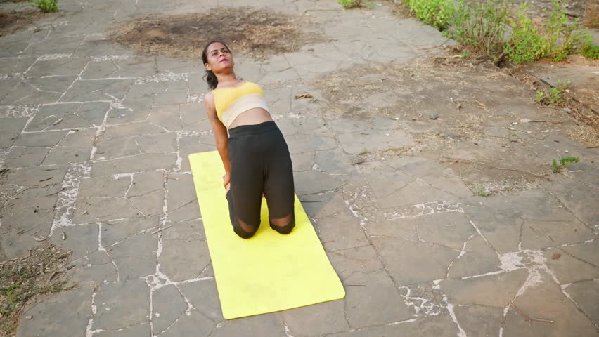 Female performs yoga in camel posture outside, Wellness seeker stretches deeply into desert pose, Lady athlete bends backward holding a position of arch, Practitioner balances, Enhancing flexibility