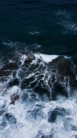 Vertical video of Drone aerial view of waves crashing on beach,Amazing sea water and sand at sunset or sunrise light,Vertical view High quality video ProRes 422,Seashore background