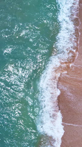 Vertical video of Drone aerial view of waves crashing on beach,Amazing sea water and sand at sunset or sunrise light,Vertical view High quality video ProRes 422,Seashore background