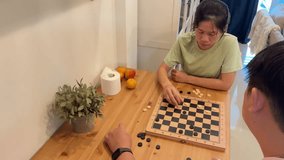 The East Asian couple is playing a game of draughts in the living room. - Powered by Shutterstock - Get 15% off with code: PIKWIZARD15