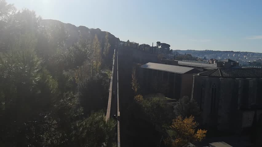 Circular panorama from Girona fortress wall captures medieval architecture and autumnal hills. Video 26 seconds. Morning light blends historic charm with modern cityscapes and distant mountains