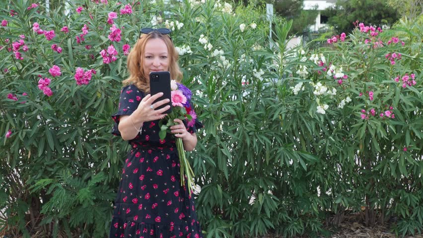 girl in a beautiful dress on a date with a bouquet of flowers beautiful, happy. Woman taking a selfie on a date, with a bouquet of flowers. smiling. happy woman walking in the park