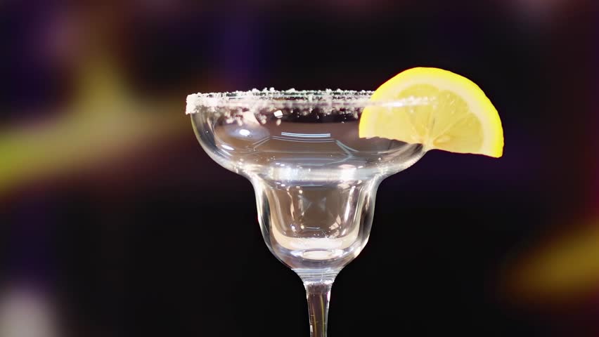A sequence of pouring blue cocktail into a glass with a lemon slice garnish, set against a dark background.