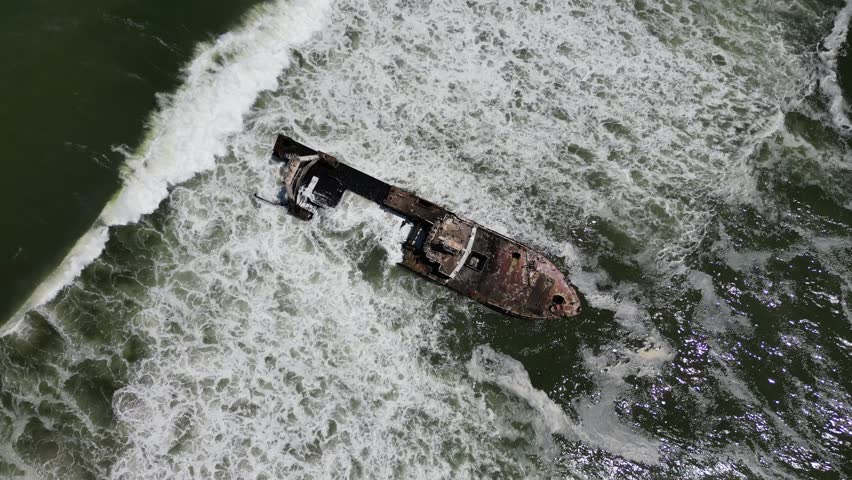 An aerial drone view of Zeila Shipwreck Namibia surrounded by foamy waves on the South Atlantic Ocean in Skeleton Coast, Jakkalsputz, Namibia