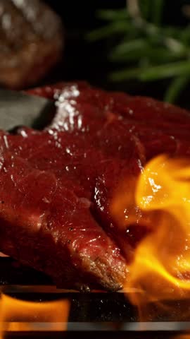 Slow Motion of Turning Beef Steak on a Grill with Roaring Flames . Filmed on High Speed Cinematic Camera at 1000 FPS .