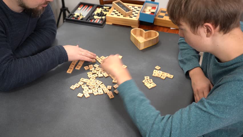 Scrabble board game. Players hands on table take letters. Family fun. Father and son spend time together. Different games