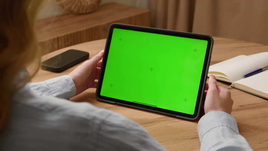 Woman sit desk use click center tech tablet, green screen mock up. Hand point ipad web site mockup. Girl hold pad press tap touch middle. Chroma key page. Cozy home background. Online app copy space.