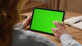 Woman sit desk use digital tech tablet with green screen mock up. Hand scroll ipad web site, swiping like photos. Girl hold pad close up. Chroma key page. Cozy home background. Online app copy space. - Powered by Shutterstock - Get 15% off with code: PIKWIZARD15