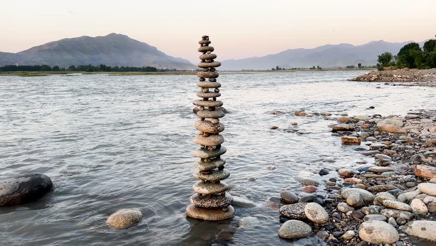 River stone sculpture or tower in a shallow water of flowing river