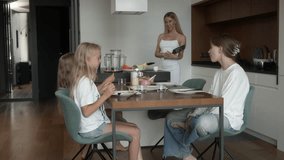 A mother engages in conversation with her three daughters while they eat pancakes at the dining table. Happy family interaction and communication during a homemade breakfast in their modern kitchen. - Powered by Shutterstock - Get 15% off with code: PIKWIZARD15