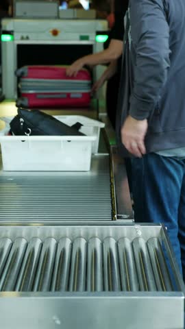 AIRPORT BORYSPIL, UKRAINE - OCTOBER 24, 2018: Male passenger puts belongings in plastic tray, box on a conveyor belt, in front of the x-ray scanner for checking baggage, hand luggage at airport