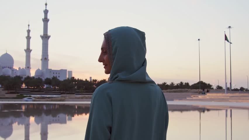 Close up Woman in traditional Arabic dress in Wahat Al Karama or Oasis of Dignity near Sheikh Zayed Grand Mosque in Abu Dhabi, showcasing cultural elegance and iconic Islamic architecture at sunset