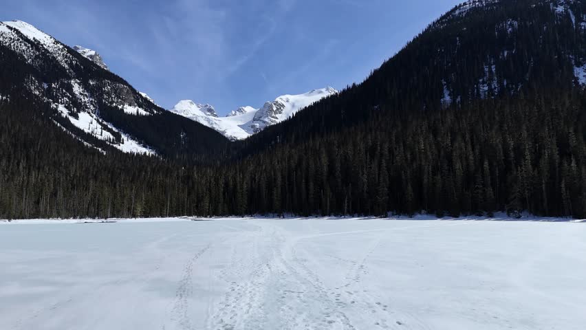 Footprints over frozen lower Joffree lake in British Columbia, Canada. Scenic and snow covered mountains in the background