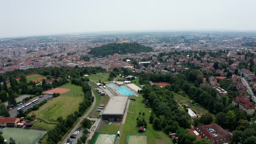 arriving drone shot of public outdoor swimming pool and castle in brno city