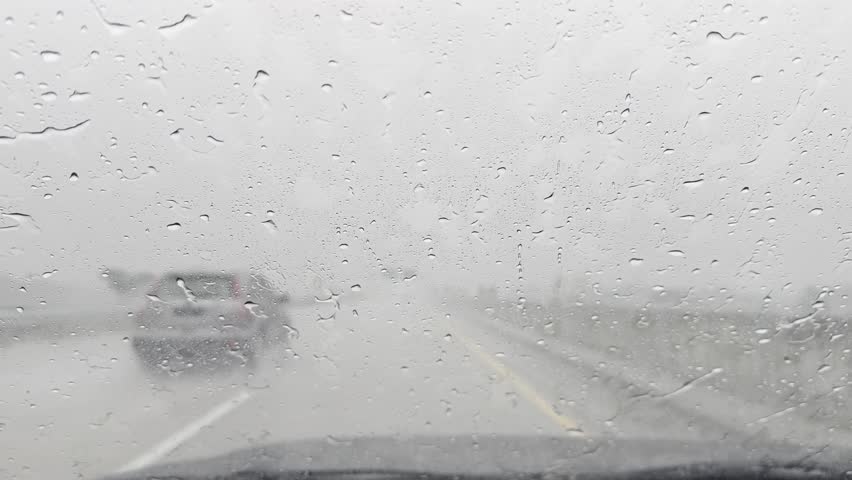 Blurry car front view driving on a highway in rain and hail in Indonesia.